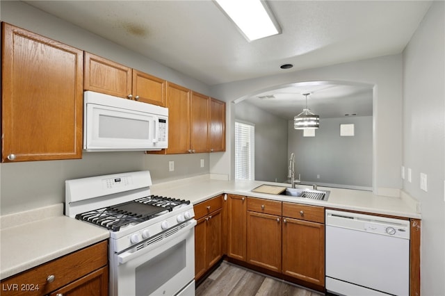 kitchen with wood-type flooring, sink, pendant lighting, a chandelier, and white appliances