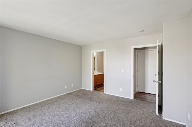 unfurnished bedroom with connected bathroom and carpet flooring