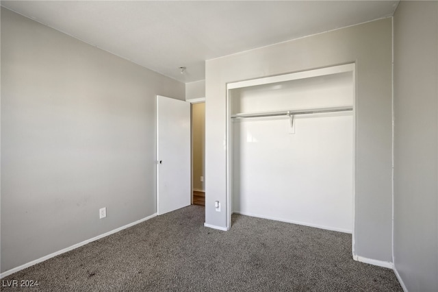 unfurnished bedroom with a closet and dark colored carpet