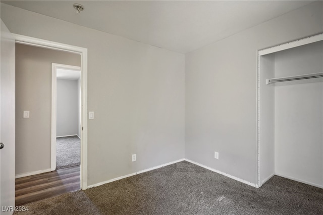 unfurnished bedroom featuring a closet and dark carpet