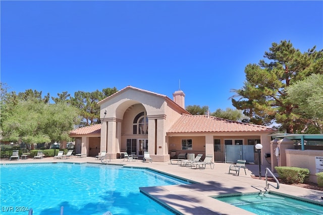 back of house with a swimming pool with hot tub and a patio