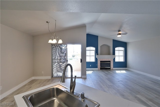 kitchen with ceiling fan with notable chandelier, wood-type flooring, lofted ceiling, and sink