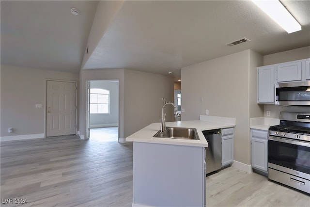 kitchen featuring kitchen peninsula, appliances with stainless steel finishes, light wood-type flooring, sink, and white cabinets