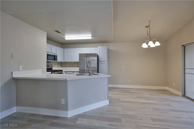 kitchen featuring kitchen peninsula, stainless steel appliances, a notable chandelier, white cabinets, and light hardwood / wood-style floors