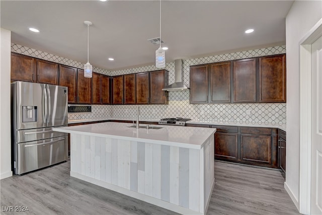 kitchen with appliances with stainless steel finishes, hanging light fixtures, sink, and wall chimney range hood