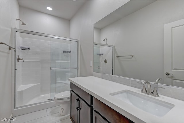 bathroom featuring vanity, tile patterned flooring, toilet, and a shower with door