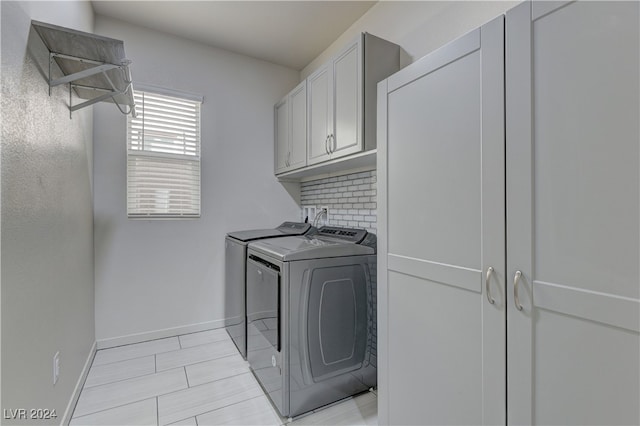 clothes washing area featuring washing machine and clothes dryer and cabinets