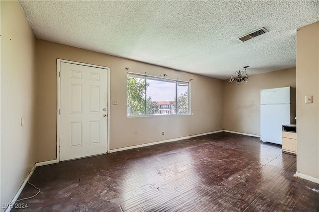 interior space featuring an inviting chandelier, a textured ceiling, and dark hardwood / wood-style floors