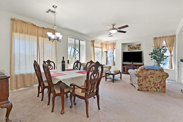 carpeted dining space with ceiling fan with notable chandelier