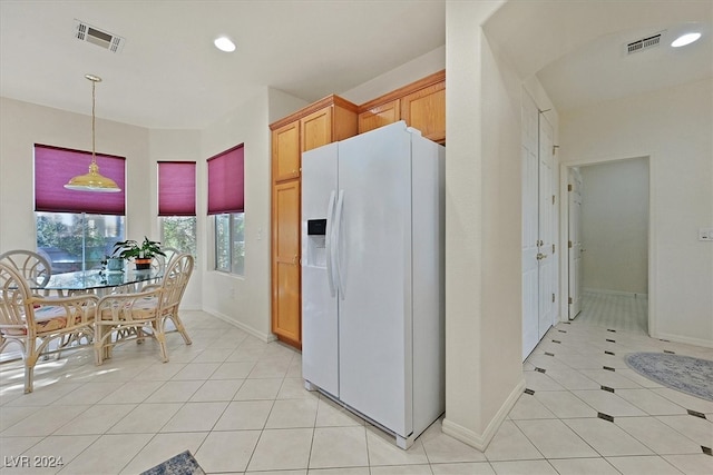 kitchen with white fridge with ice dispenser, hanging light fixtures, and light tile patterned floors