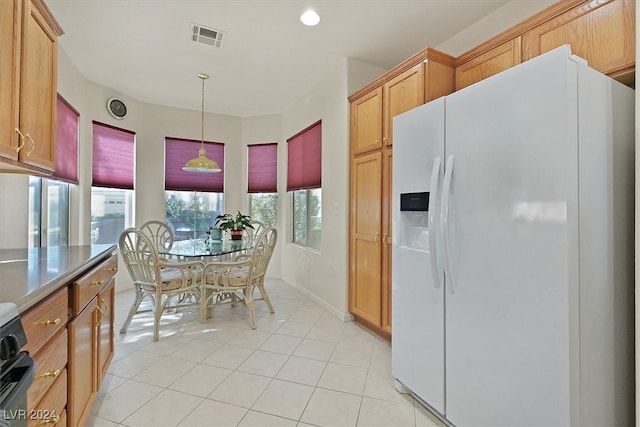 kitchen featuring pendant lighting, white fridge with ice dispenser, and light tile patterned floors