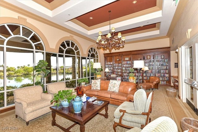 living room featuring a towering ceiling, a water view, a raised ceiling, and a notable chandelier