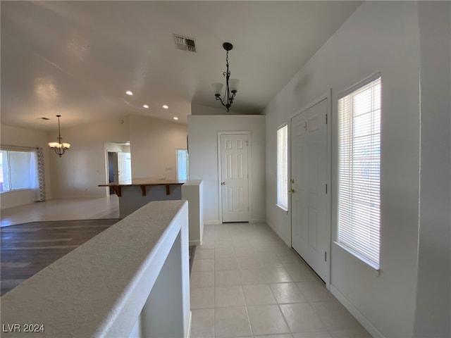 foyer entrance featuring an inviting chandelier, light wood-type flooring, and vaulted ceiling