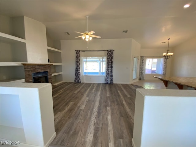 unfurnished living room with dark wood-type flooring, vaulted ceiling, built in shelves, and a healthy amount of sunlight