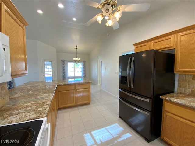 kitchen with decorative backsplash, black fridge, lofted ceiling, kitchen peninsula, and white range oven