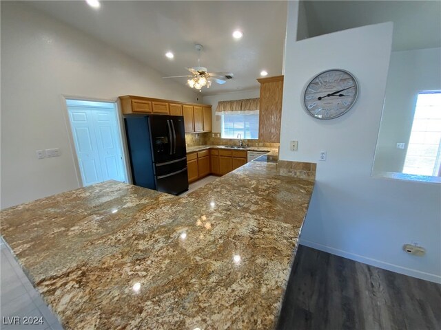 kitchen with black refrigerator with ice dispenser, kitchen peninsula, sink, and a healthy amount of sunlight