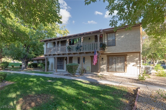 view of front of property with a front yard and a balcony