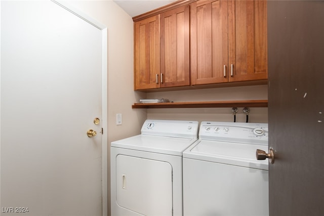 washroom with washer and dryer and cabinets