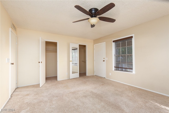 unfurnished bedroom featuring ceiling fan, light colored carpet, and a textured ceiling