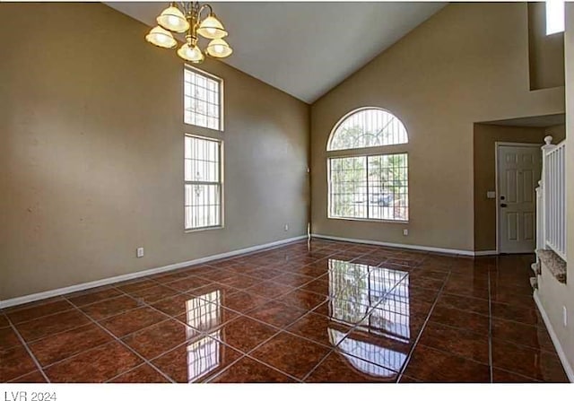 tiled empty room with a notable chandelier, plenty of natural light, and high vaulted ceiling