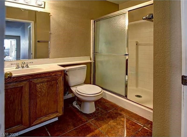 bathroom with tile patterned flooring, a shower with door, vanity, and toilet