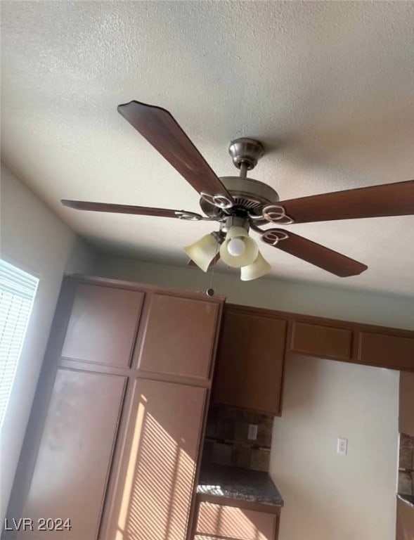 interior details featuring ceiling fan and a textured ceiling