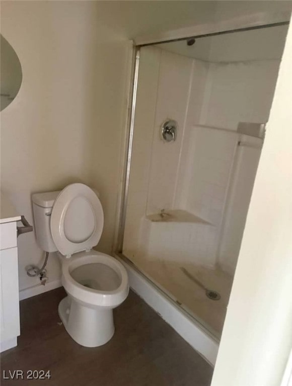 bathroom featuring hardwood / wood-style floors, vanity, toilet, and a shower with door