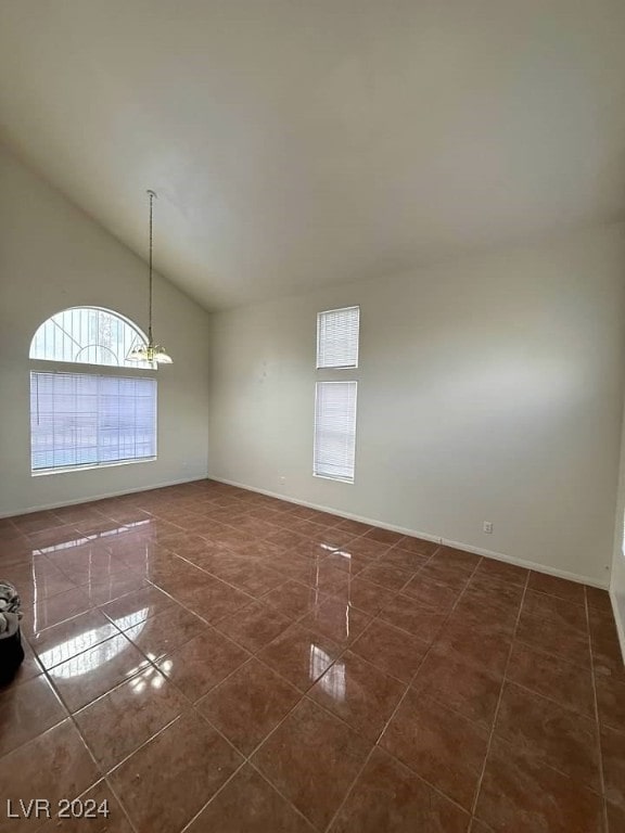 empty room with dark tile patterned floors and an inviting chandelier