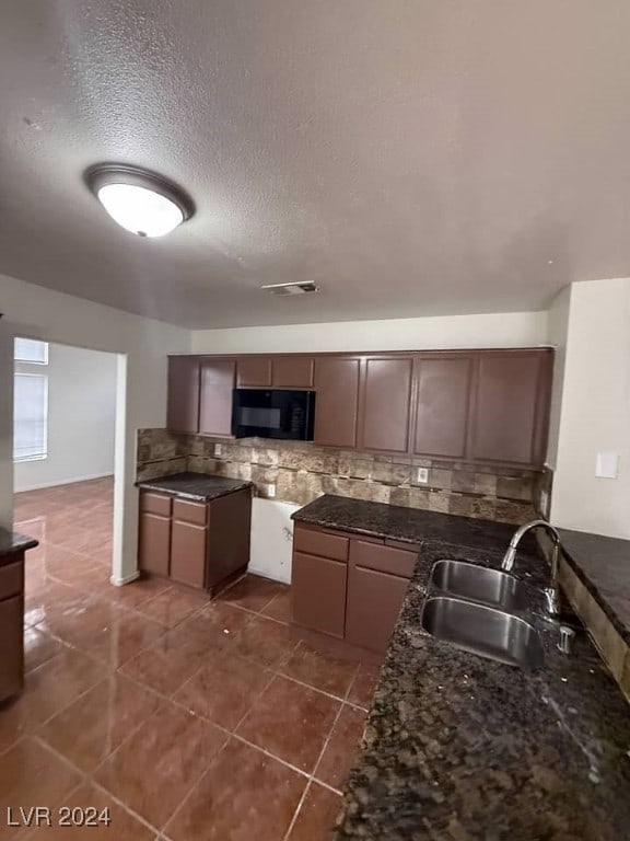 kitchen featuring a textured ceiling, decorative backsplash, sink, and dark tile patterned flooring