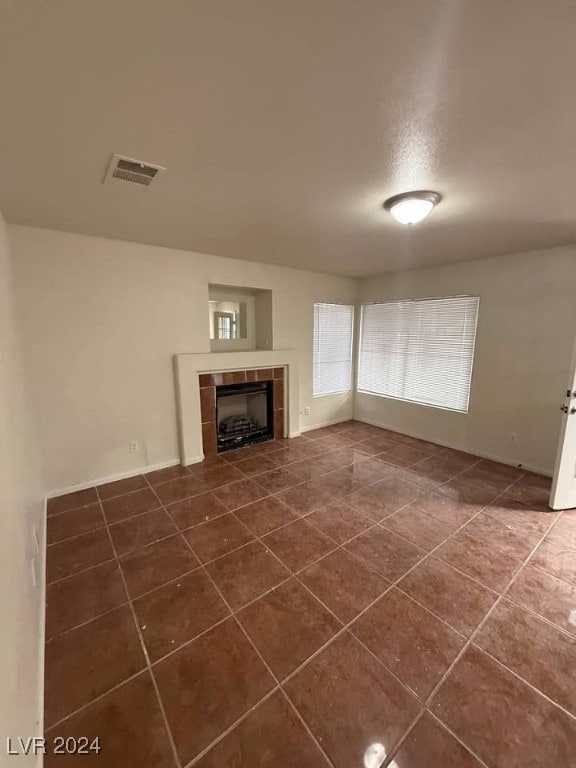 unfurnished living room featuring dark tile patterned floors and a tile fireplace