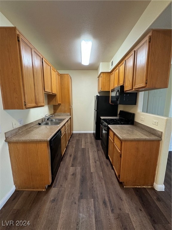 kitchen with dark hardwood / wood-style floors, black appliances, sink, and a textured ceiling