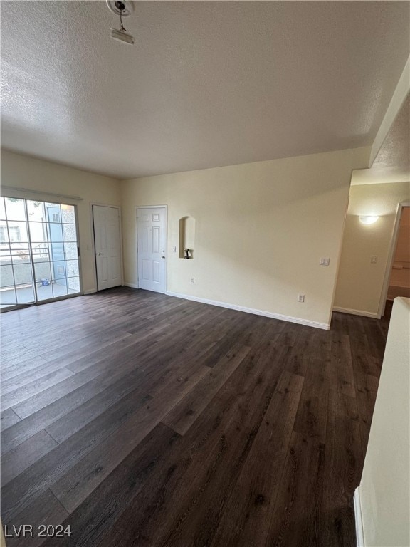 unfurnished living room featuring a textured ceiling and dark wood-type flooring