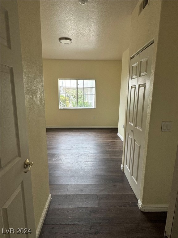 empty room with dark wood-type flooring and a textured ceiling