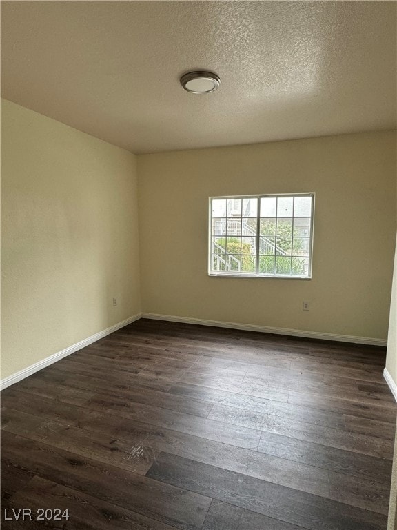 unfurnished room featuring a textured ceiling and dark hardwood / wood-style flooring