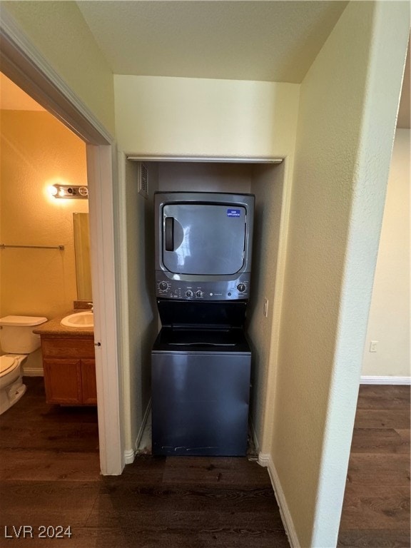 washroom with dark hardwood / wood-style floors and stacked washer / dryer