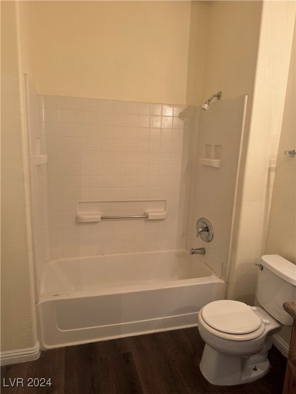 bathroom with hardwood / wood-style flooring, washtub / shower combination, and toilet