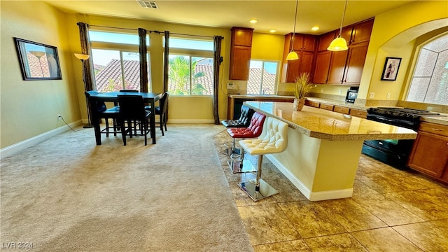 kitchen featuring black range oven, a kitchen breakfast bar, decorative light fixtures, and a healthy amount of sunlight