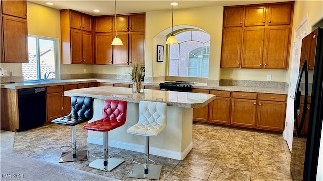 kitchen featuring pendant lighting, black appliances, a healthy amount of sunlight, and a breakfast bar