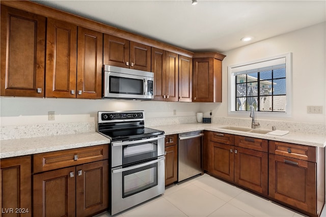 kitchen featuring light stone countertops, appliances with stainless steel finishes, and sink