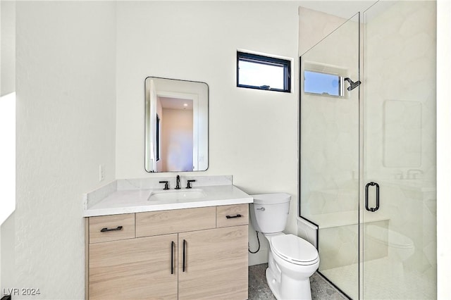 bathroom featuring vanity, a shower with shower door, and toilet