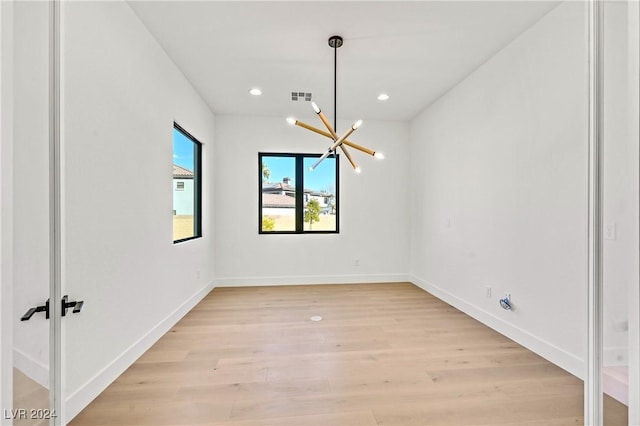 empty room featuring a chandelier and light hardwood / wood-style flooring