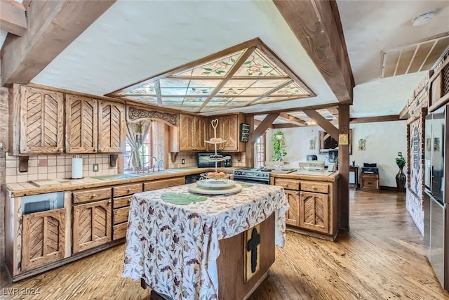 kitchen featuring gas stove, light wood-type flooring, tasteful backsplash, and a center island