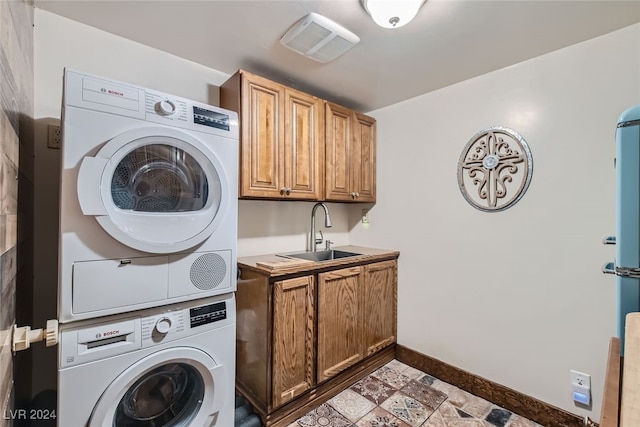 laundry area featuring cabinets, sink, and stacked washer / drying machine