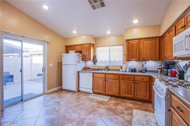 kitchen with light tile patterned floors, white appliances, vaulted ceiling, and sink