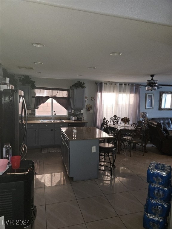 kitchen featuring black fridge, a kitchen island, dark tile patterned flooring, and sink