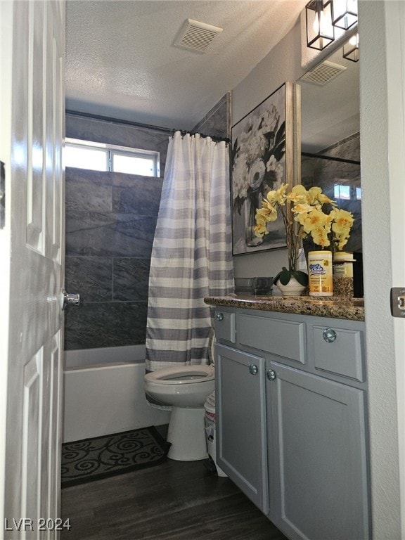 full bathroom featuring vanity, wood-type flooring, a textured ceiling, shower / bath combo with shower curtain, and toilet