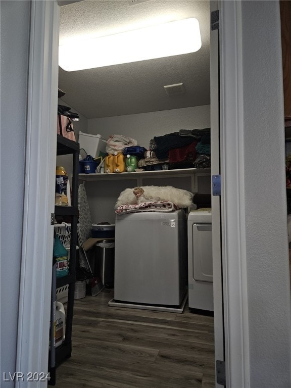 clothes washing area with dark wood-type flooring, separate washer and dryer, and a textured ceiling