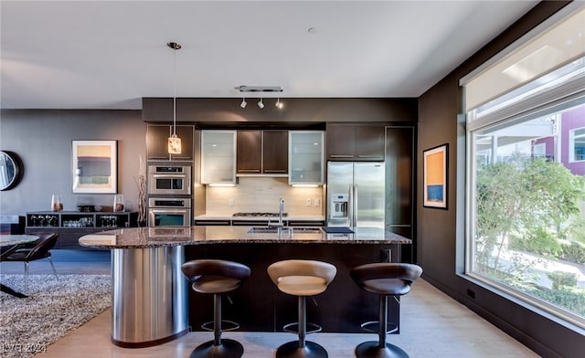 kitchen with appliances with stainless steel finishes, backsplash, sink, and a breakfast bar