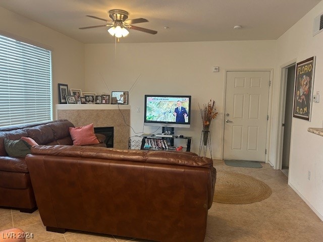 tiled living room featuring ceiling fan and a tiled fireplace