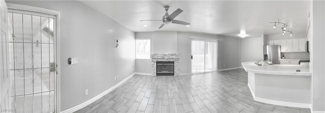 kitchen with a stone fireplace, hardwood / wood-style flooring, stainless steel appliances, white cabinets, and ceiling fan